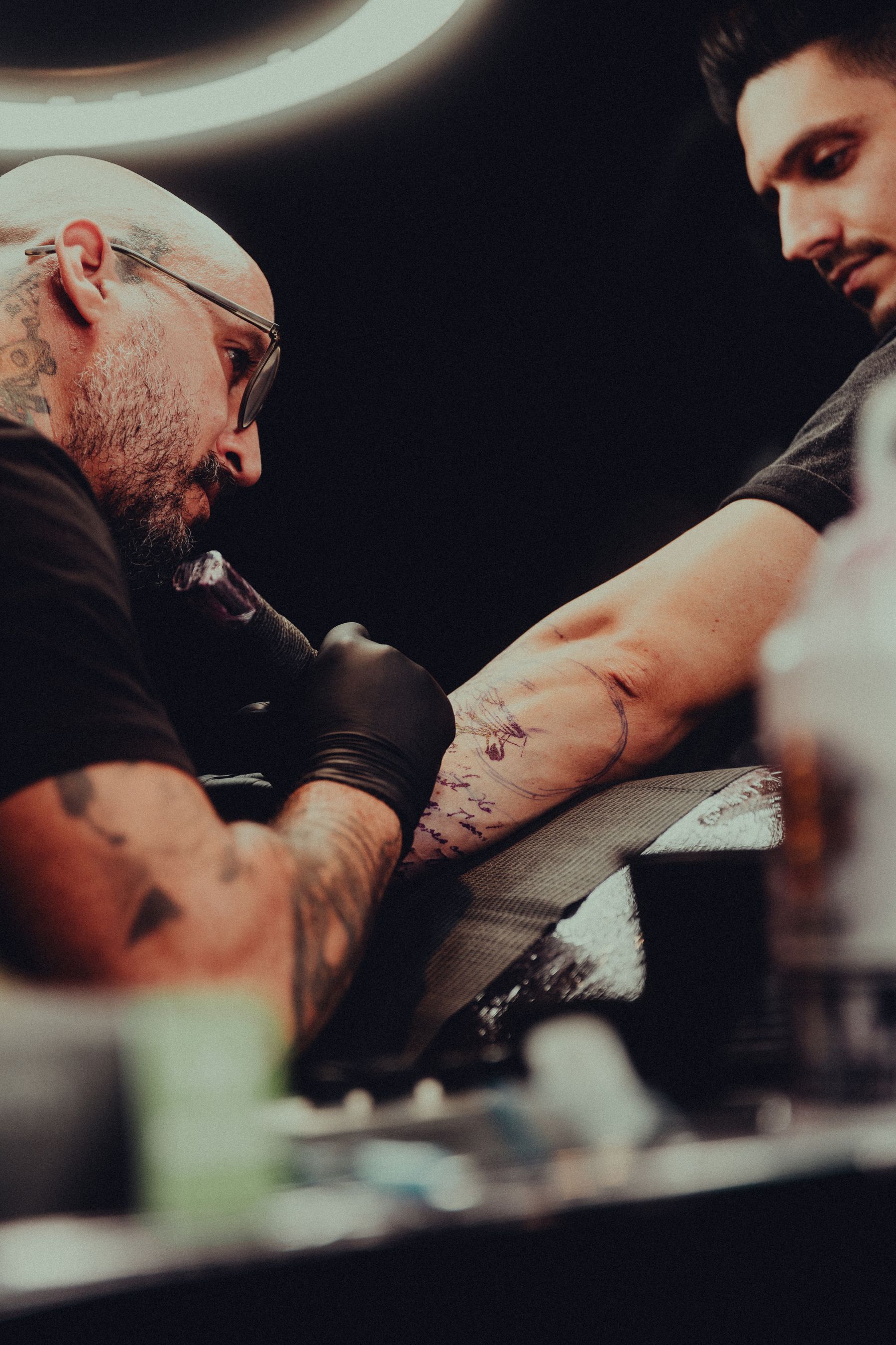 Tattoo artist working carefully with a client in a dark studio